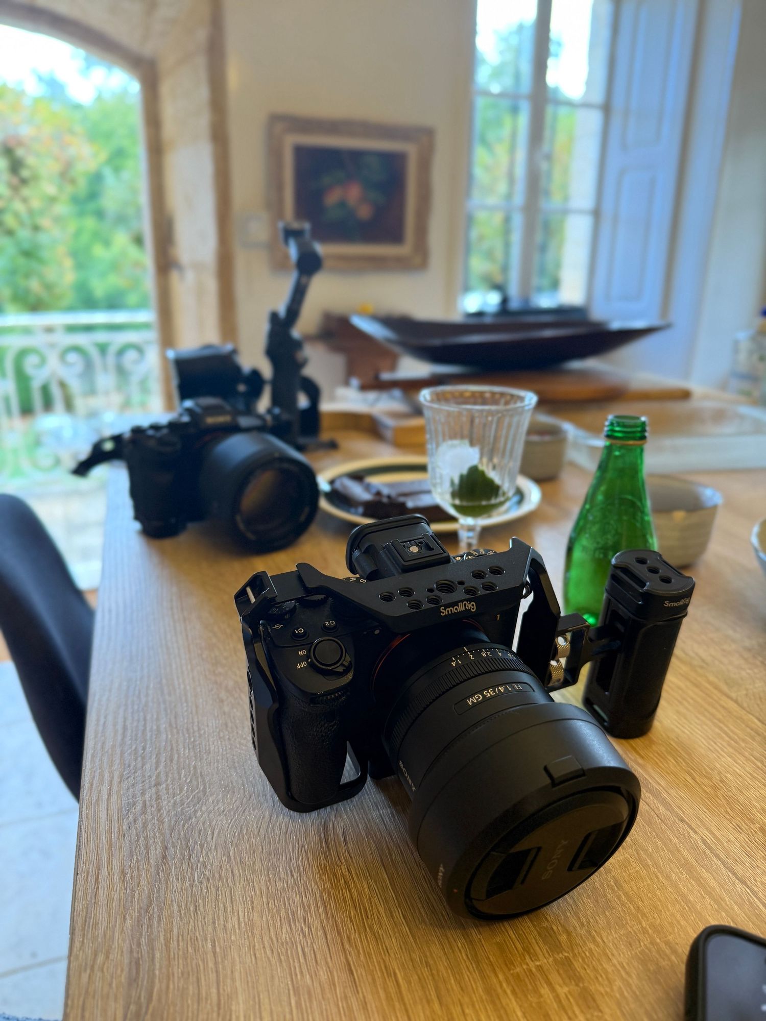 Black camera equipment displayed on wooden table near window with natural light.