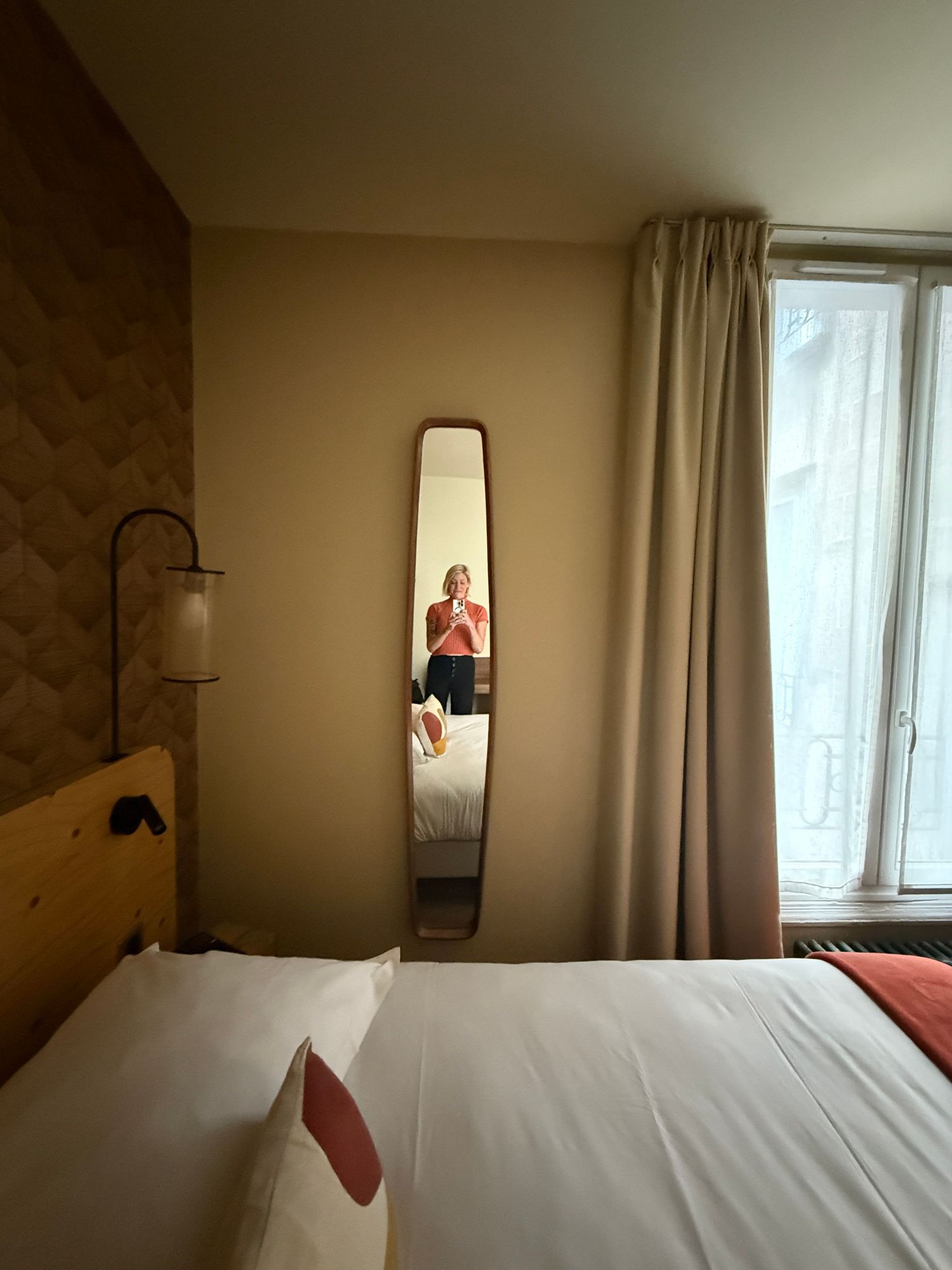 Modern hotel room interior with white bedding and beige walls lit by natural light.