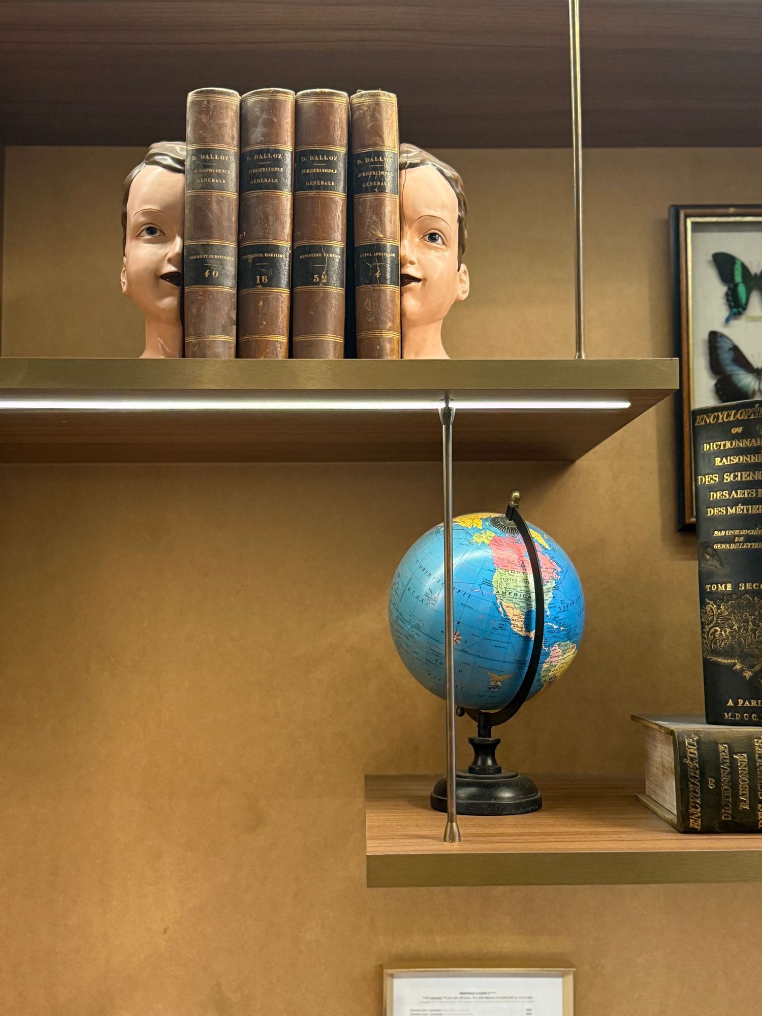 Decorative bookshelves with vintage books and blue globe ornaments in a study room.