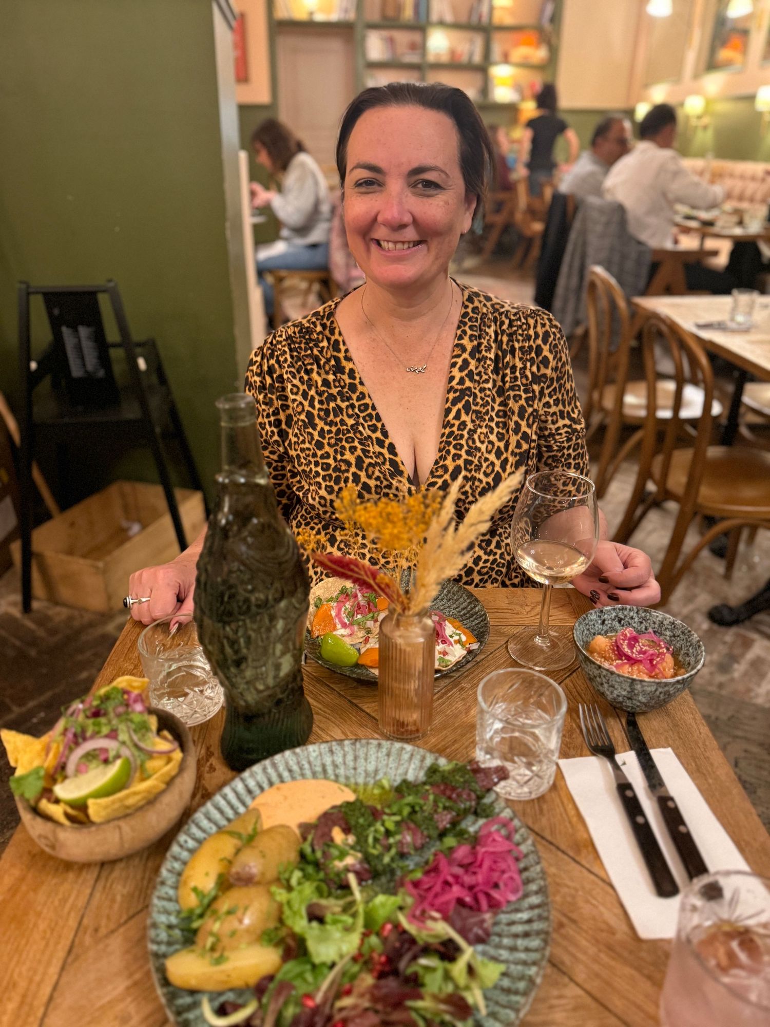 Colorful burgers and salads served on wooden boards at a restaurant table.
