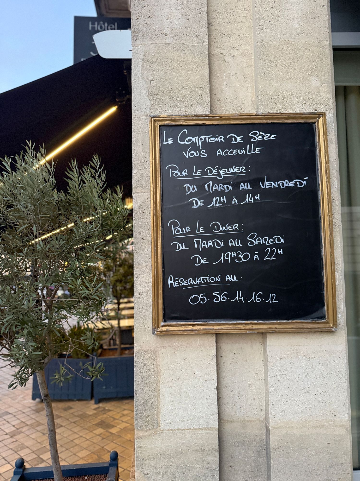French menu written on black chalkboards mounted on stone walls.