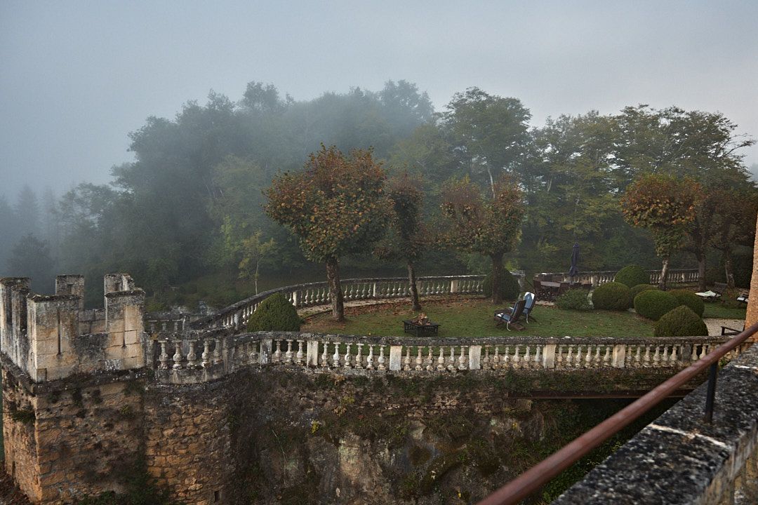 Ancient stone fortress walls and walkways shrouded in misty fog create a mysterious atmosphere.