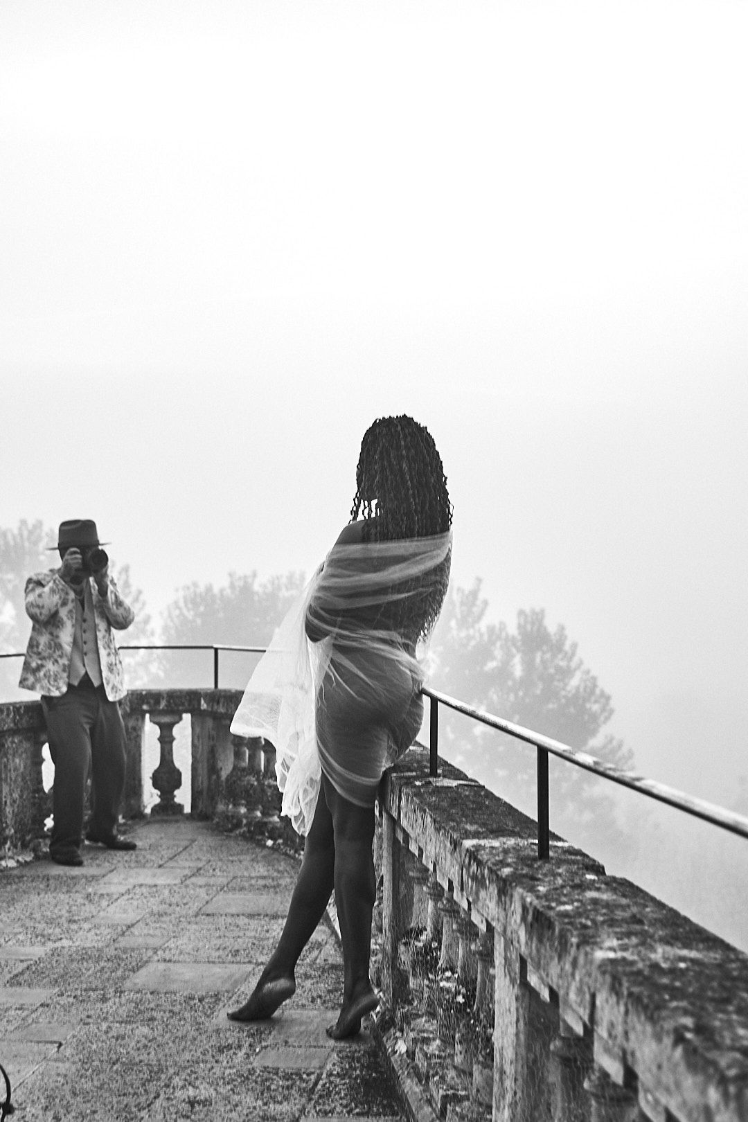 Visitors explore a historic stone wall overlook on a foggy day.