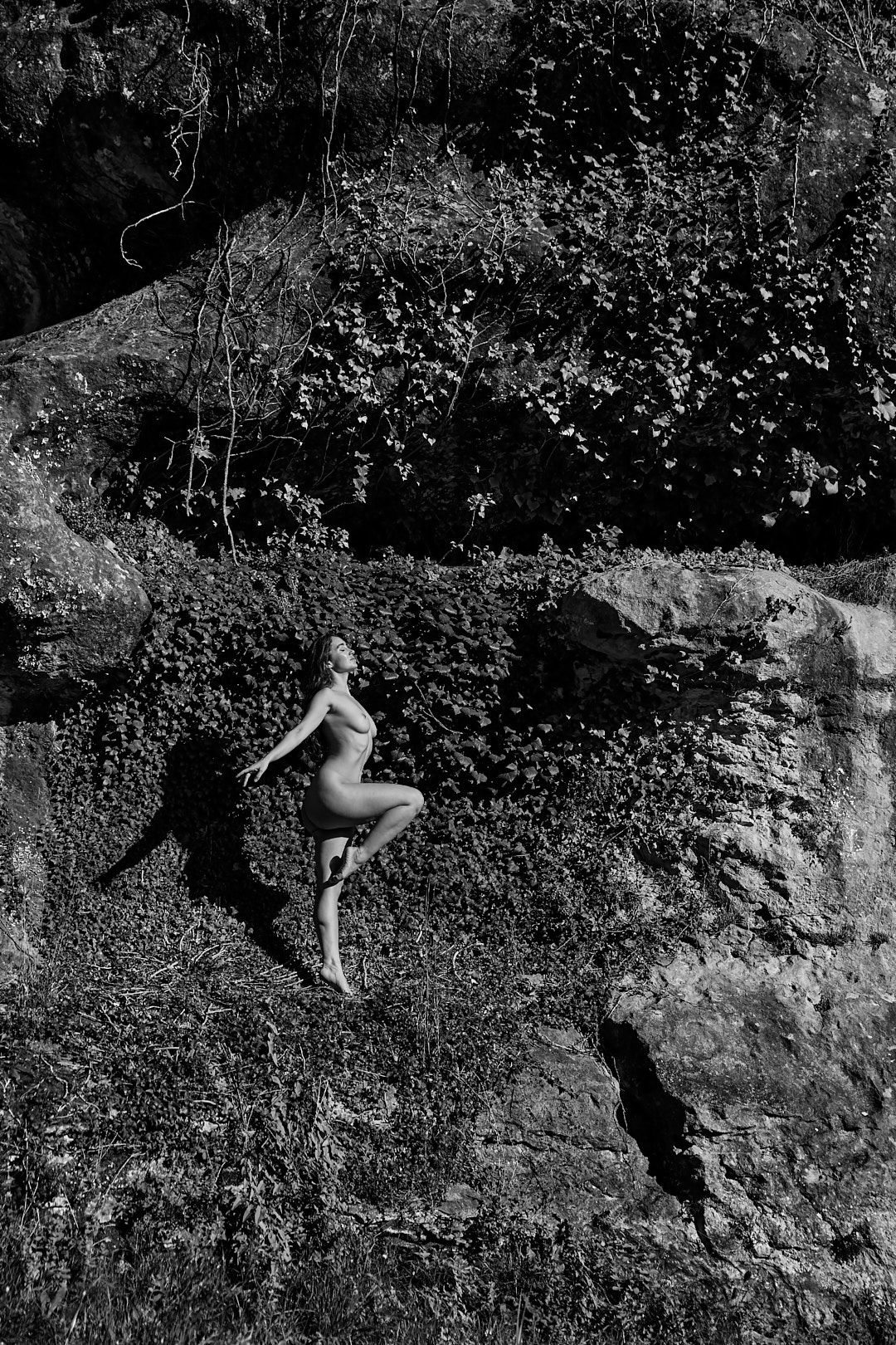 Rock climber ascending challenging limestone routes in black and white photography.