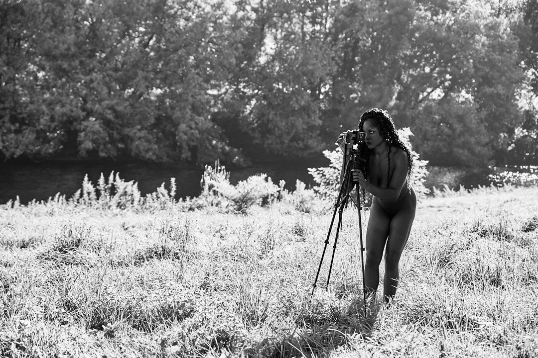 Photographer with tripod capturing scenic views in misty meadow.