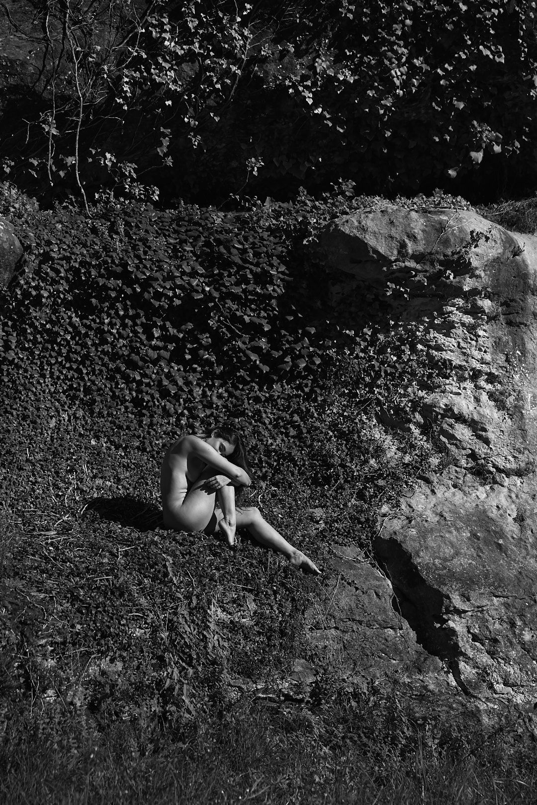 Rock climber traversing horizontal limestone route in dramatic black and white.