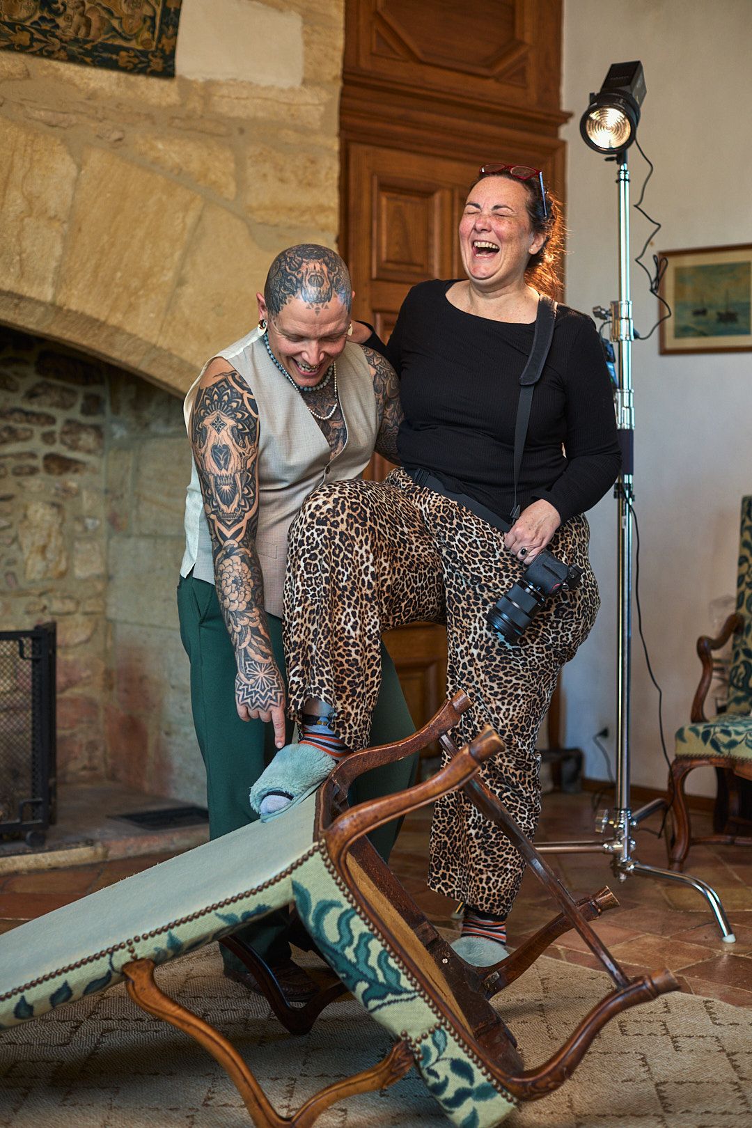 People sharing a playful moment on a vintage wooden lounge chair during a photo shoot.