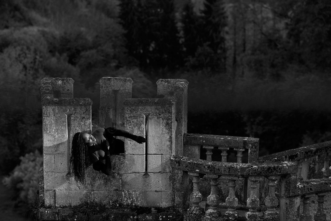 Dark atmospheric black and white photo of ancient stone ruins in a misty forest.