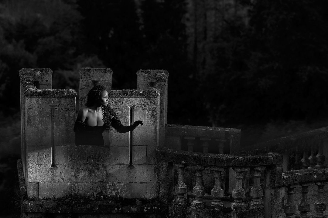 Moody black and white photograph of a stone balustrade against a dark background.