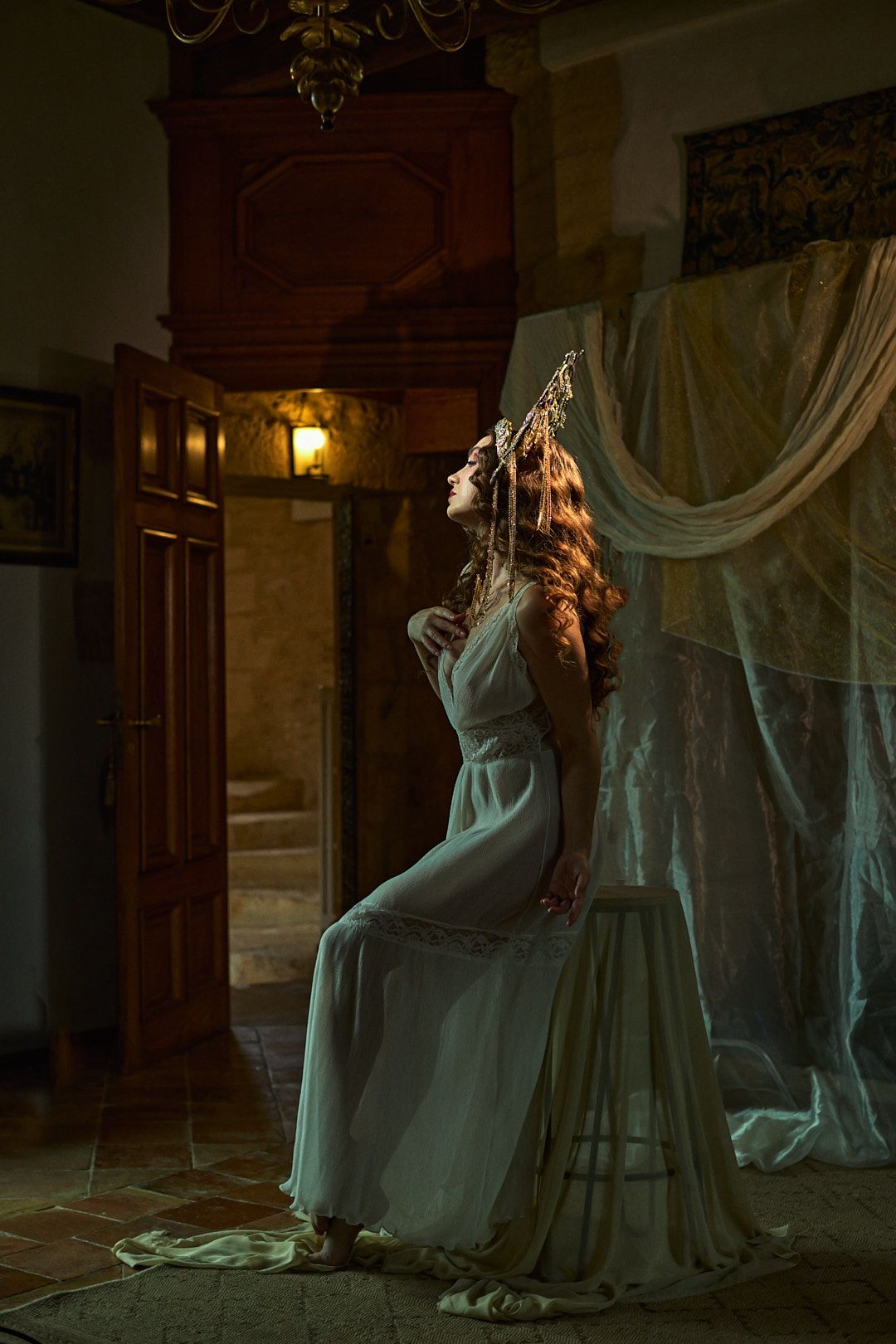 Ethereal photo of a flowing white dress against antique wooden paneling in dramatic lighting.
