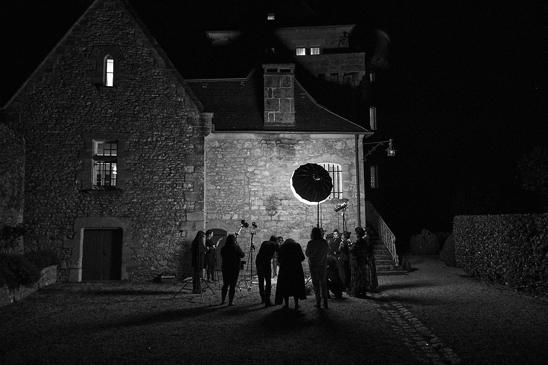 Silhouetted group of people gathered outside a stone building at night.
