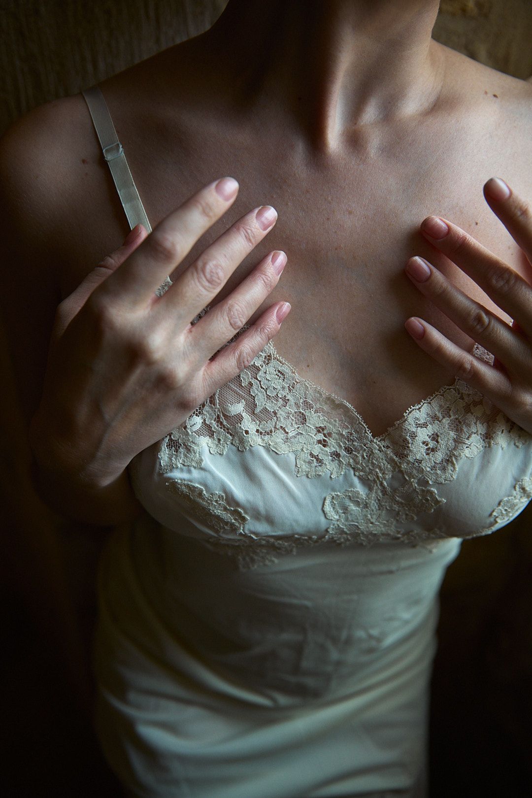 Close-up detail shot of hands on white lace corset bodice.