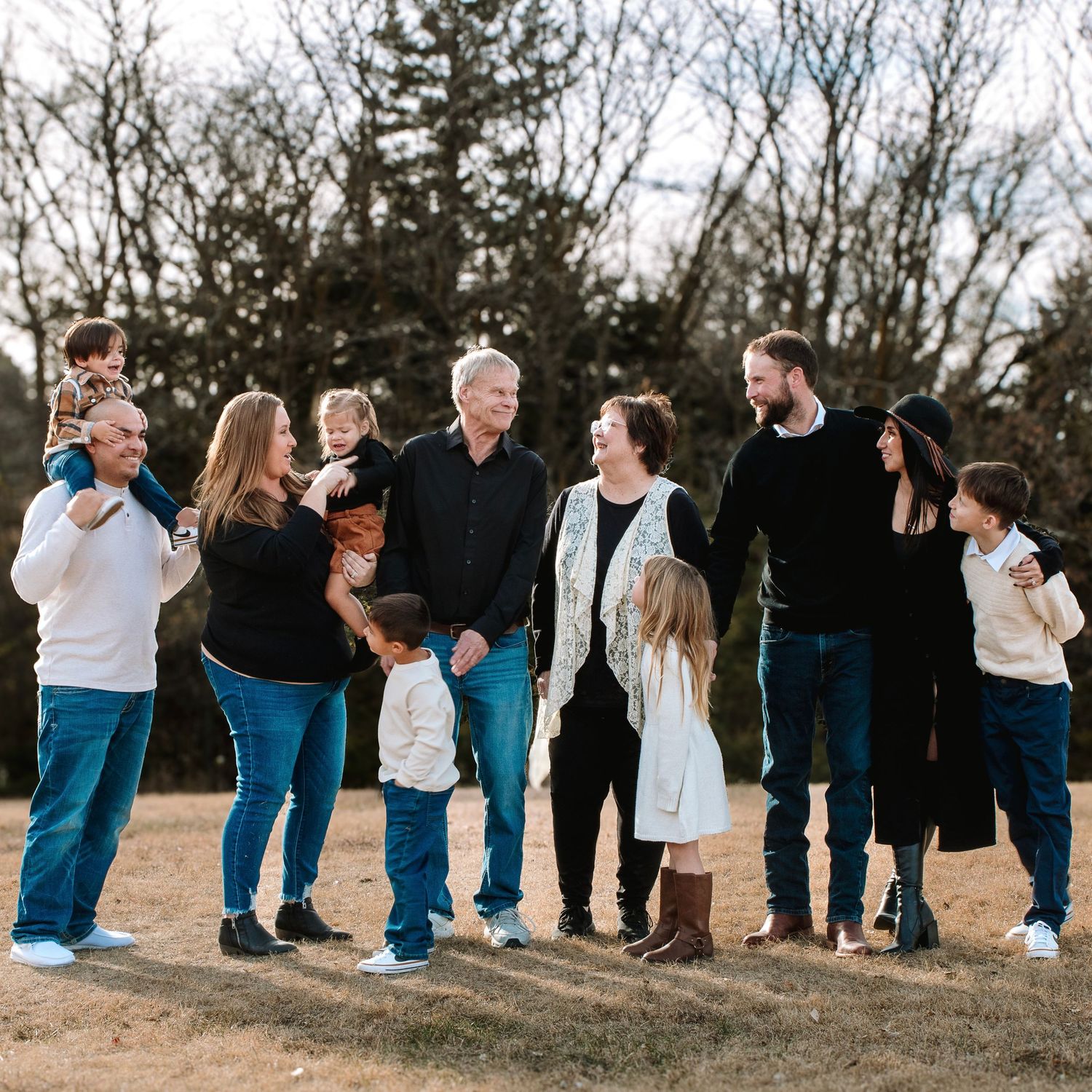 A group in coordinating blue and white outfits poses together in a natural outdoor setting during golden hour.