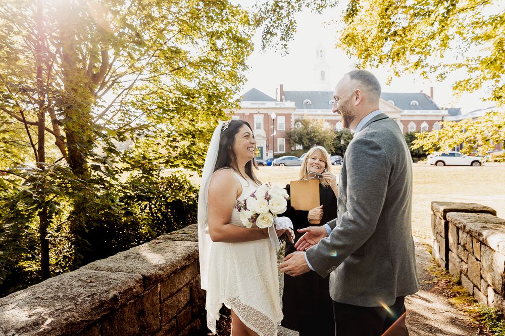 A romantic outdoor wedding photoshoot with a couple in formal attire surrounded by autumn foliage and natural light.