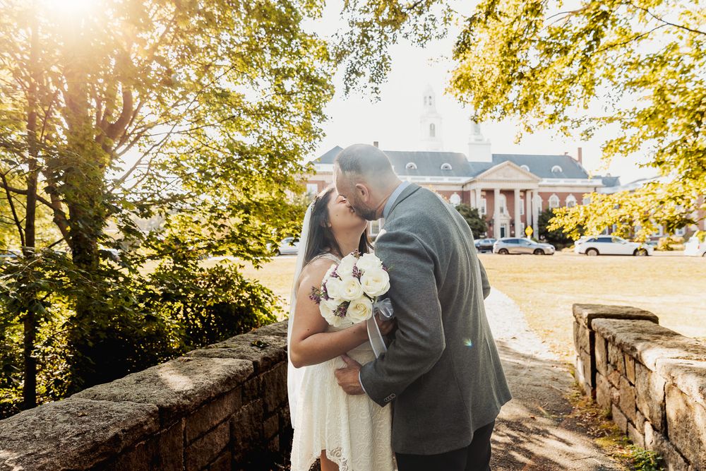Newlywed couple walks hand in hand through a sun-dappled garden path during their autumn wedding celebration.
