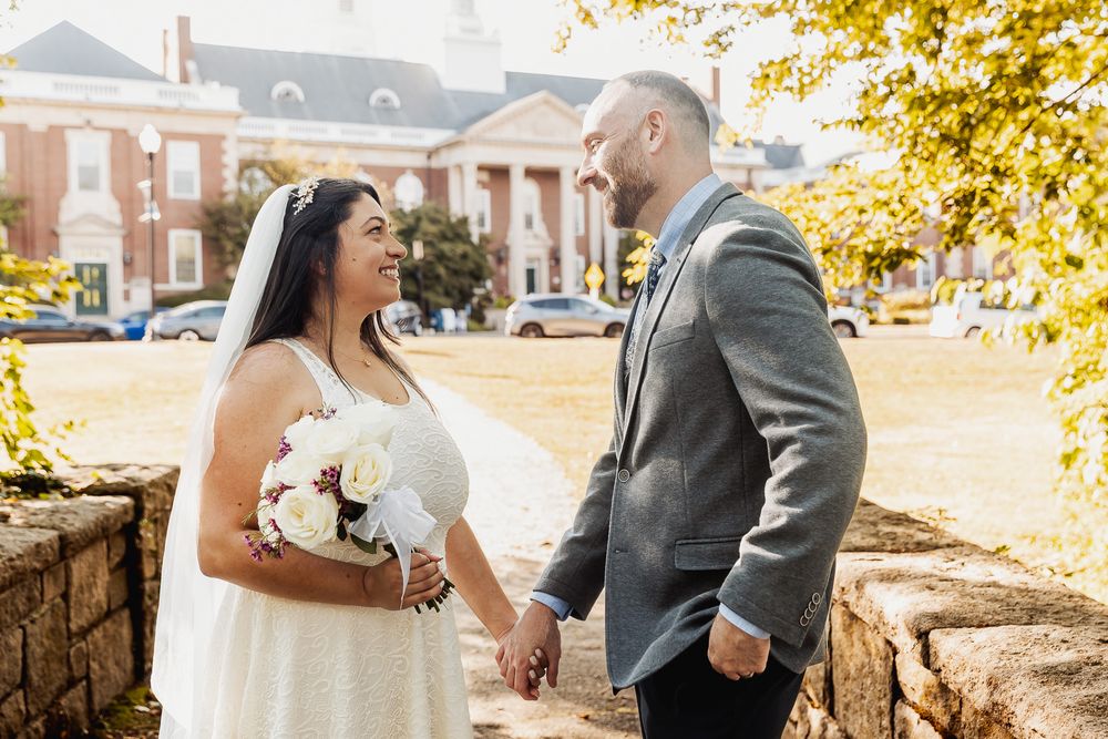 A couple in wedding attire shares an intimate moment outdoors during autumn with golden leaves in the background.
