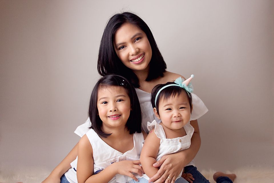 Candid family portrait showing joyful expressions against neutral backdrop.