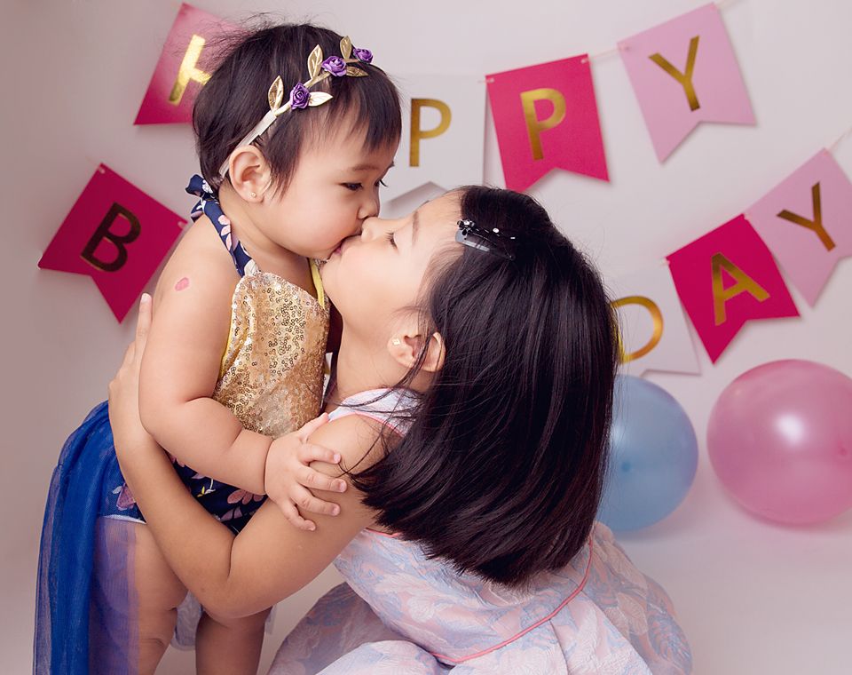 Playful family photo session with pink party decorations and balloons.