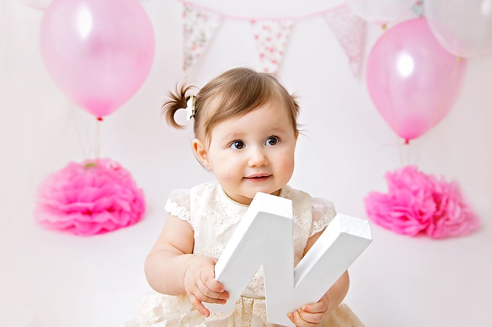 Birthday celebration with white letters, pink balloons and floral bunting.