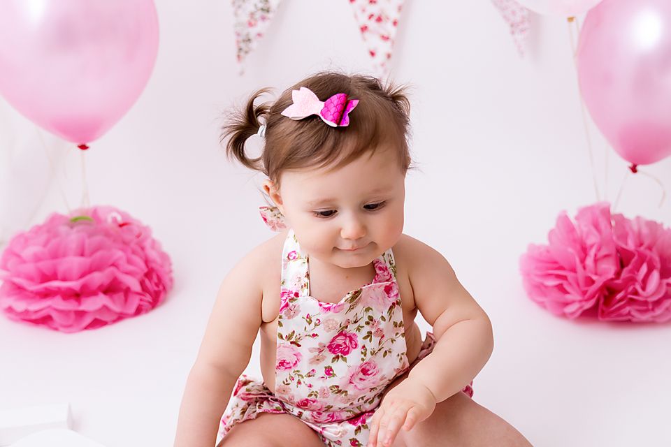 Birthday photoshoot with floral dress, pink bow and pink balloon decorations.