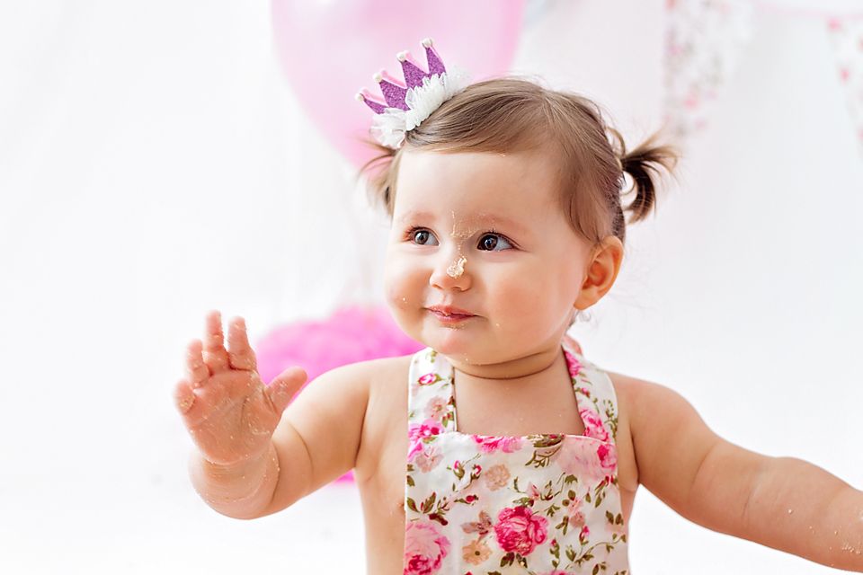Birthday celebration with tiny crown, floral dress and pink decorations.