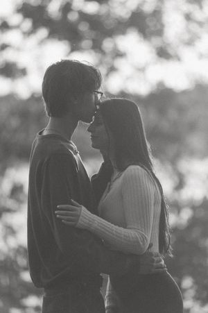 A romantic black and white portrait of a couple embracing in soft natural light.