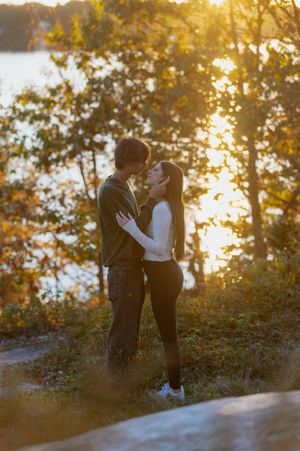A couple shares a tender moment against a golden sunset backdrop.