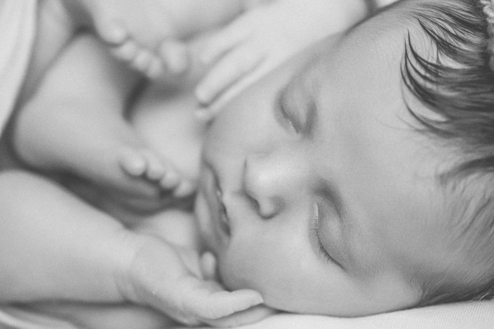 Close up black and white photo of a sleeping child with peaceful expression in soft lighting.