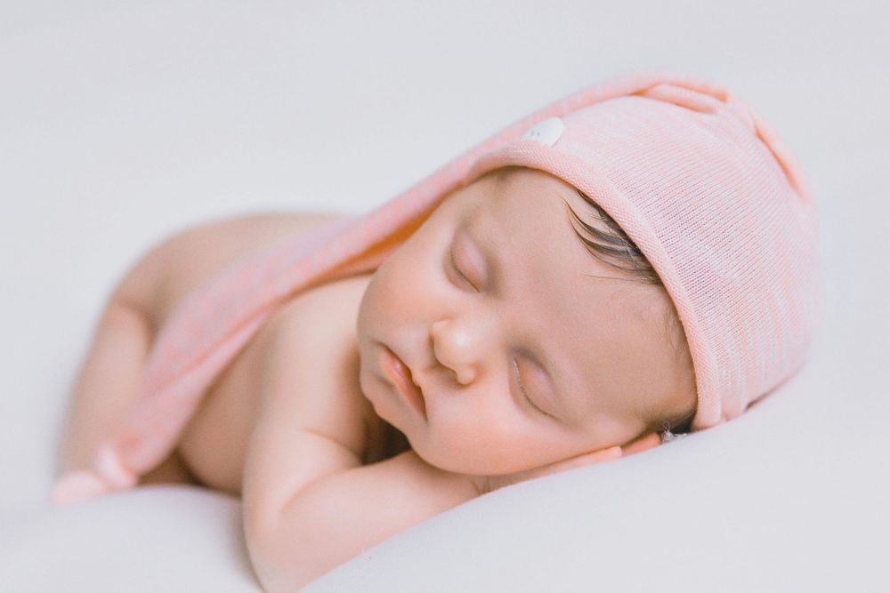 A sleeping baby wrapped in pink blankets shown from different angles in a series of four photos.