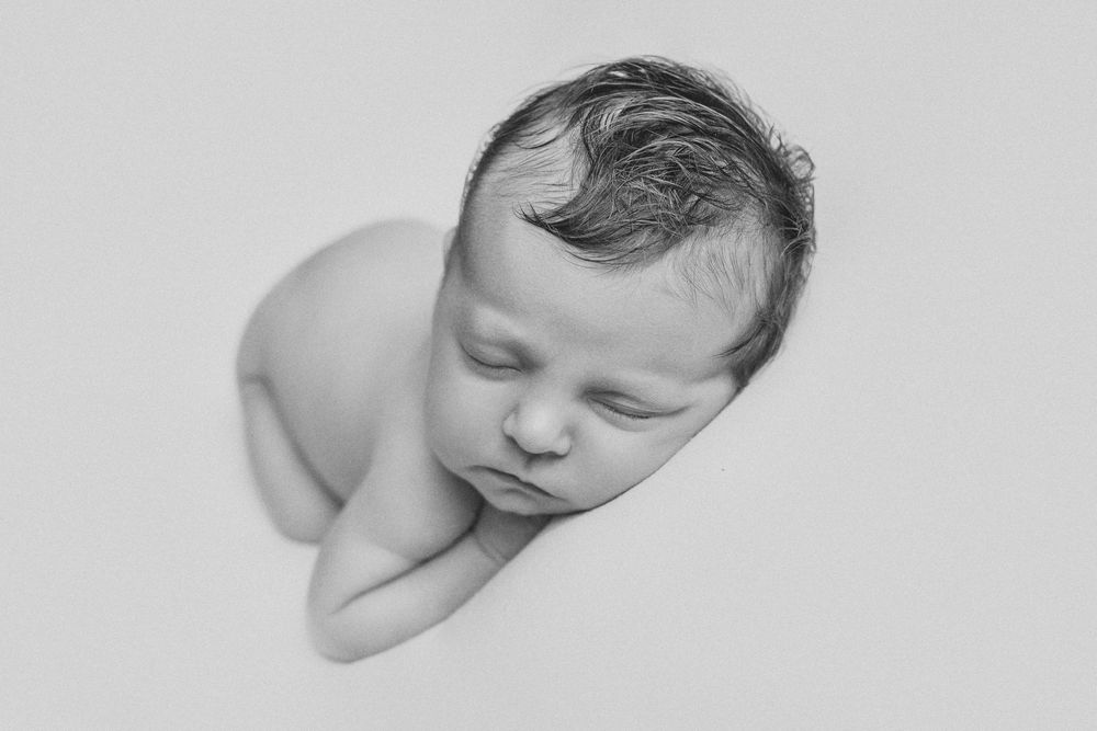 A series of artistic black and white newborn baby portraits showing peaceful sleeping poses.