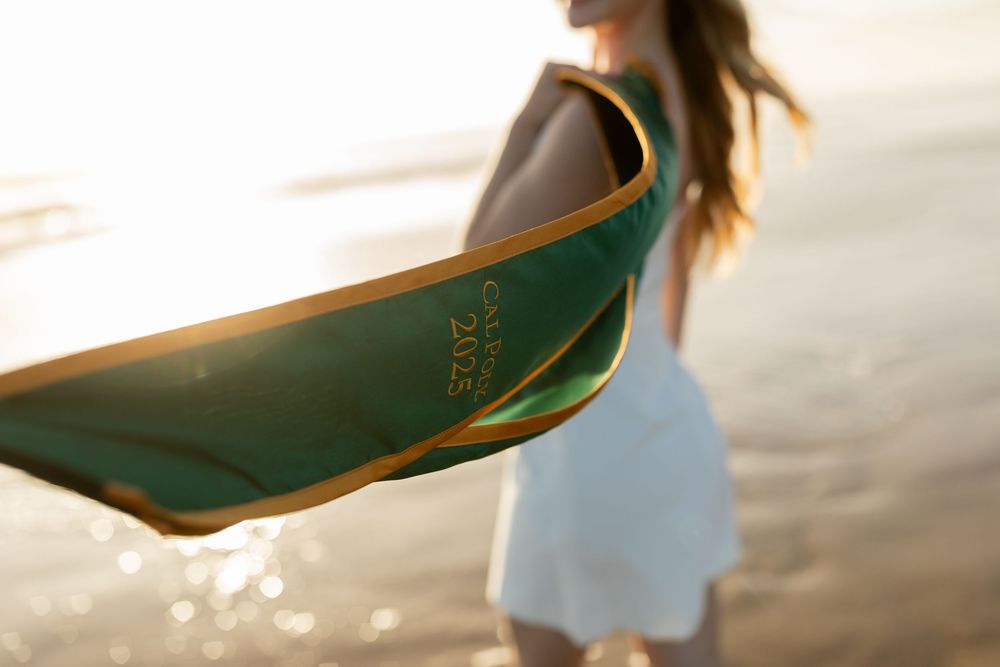 A green surfboard silhouetted against golden sunlight at the beach with a blurred figure in the background.