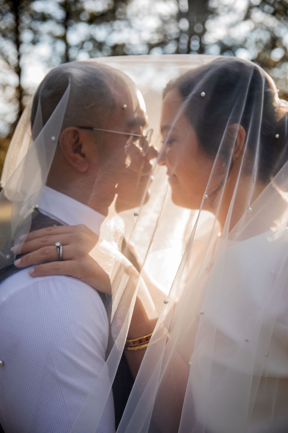 Romantic wedding portraits with sunlight and veil creating dreamy atmosphere.