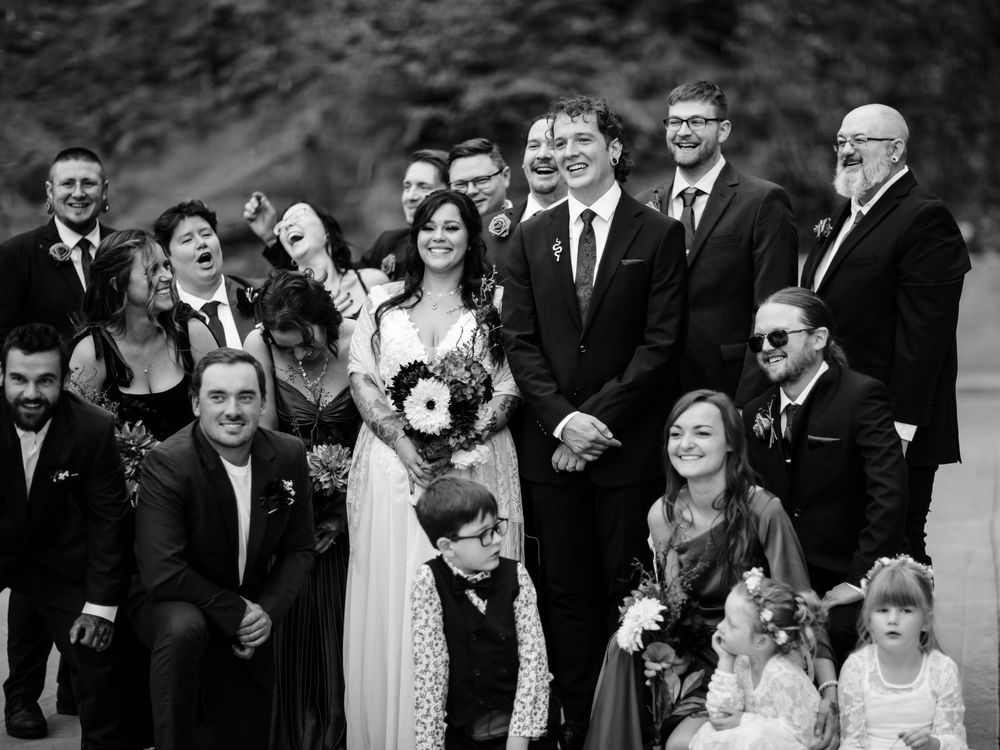 Wedding party gathered outside in formal attire for a group photo.
