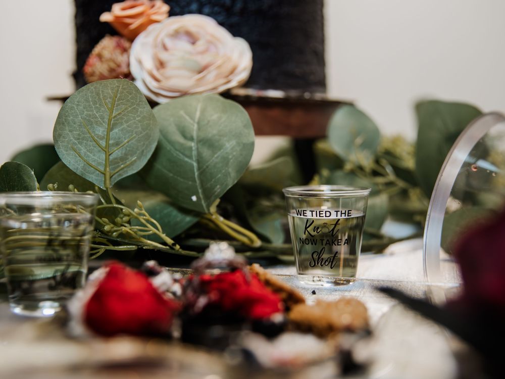 Table setting with roses, eucalyptus leaves and cocktail glasses in soft lighting.