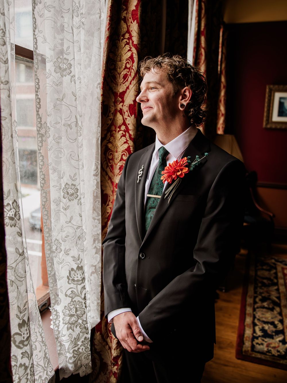 Elegant lace curtains frame a window in a formal room with rich red walls.