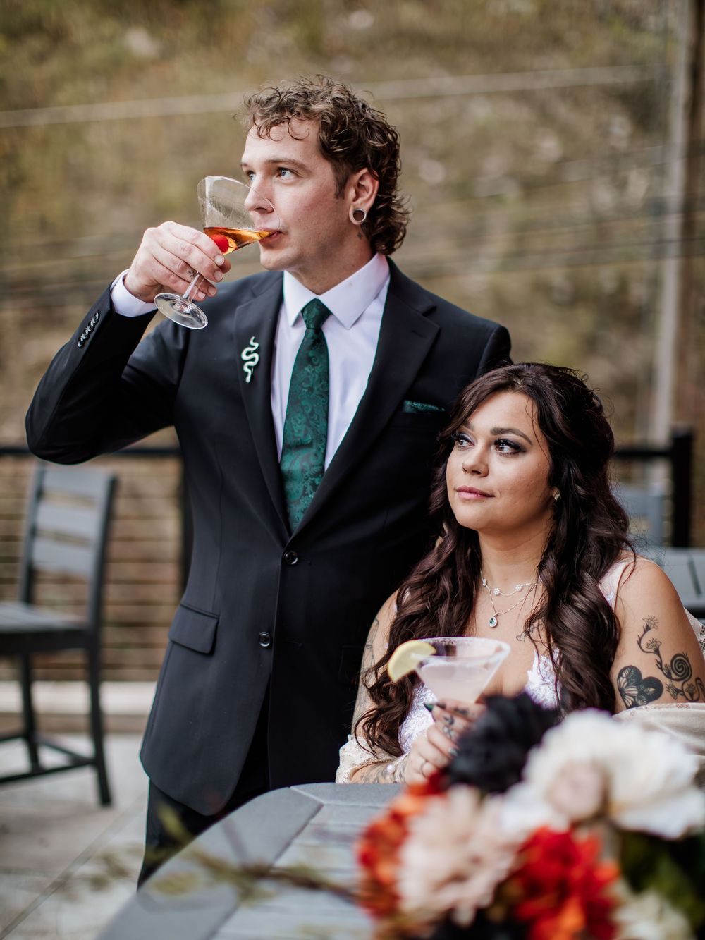 Wedding party members in formal attire with red floral accents outdoors.