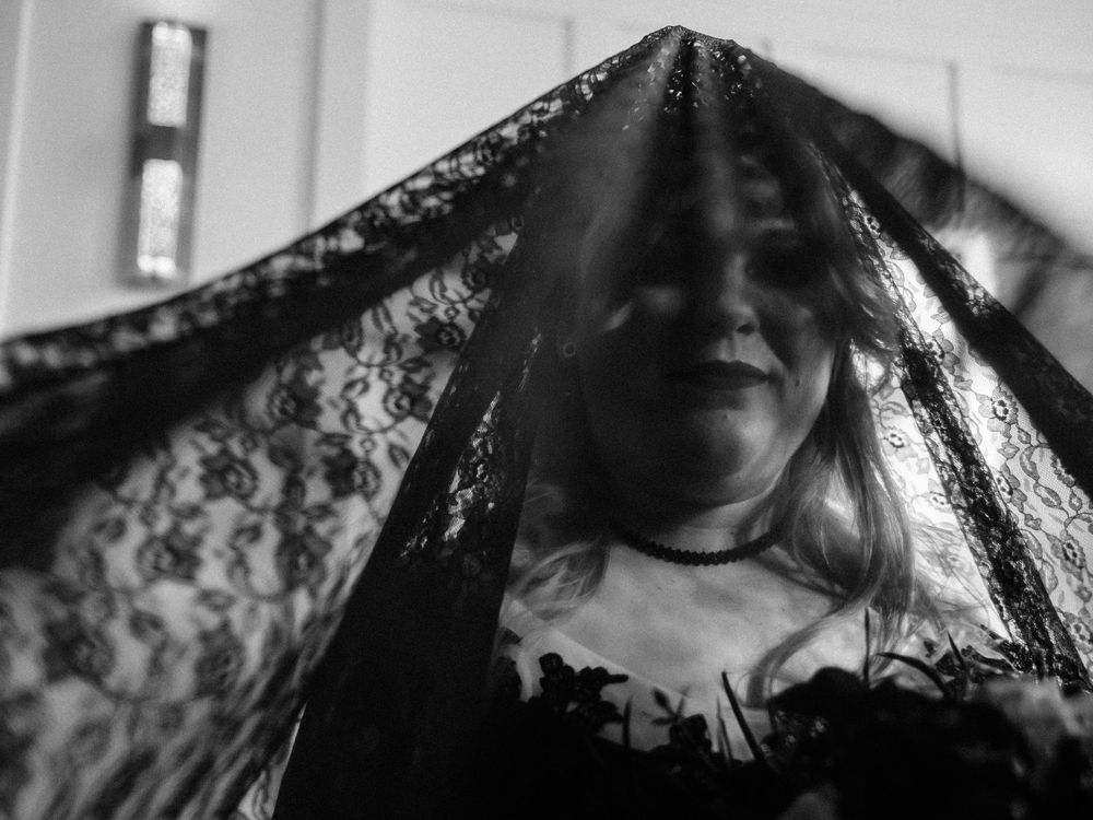 Moody black and white portrait of figure in dark lace veil.