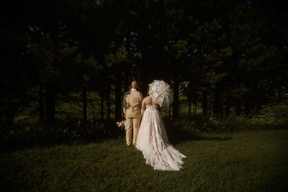 A wedding couple shares an intimate moment in a forest setting at dusk.