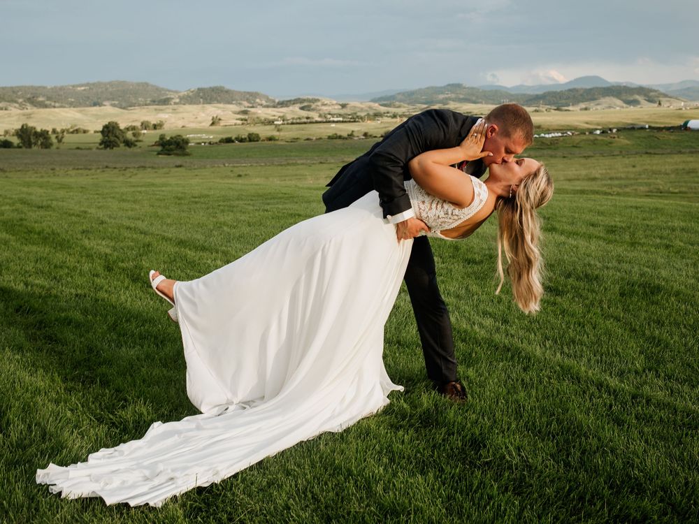 White wedding dress billowing in the wind against a scenic mountain landscape.