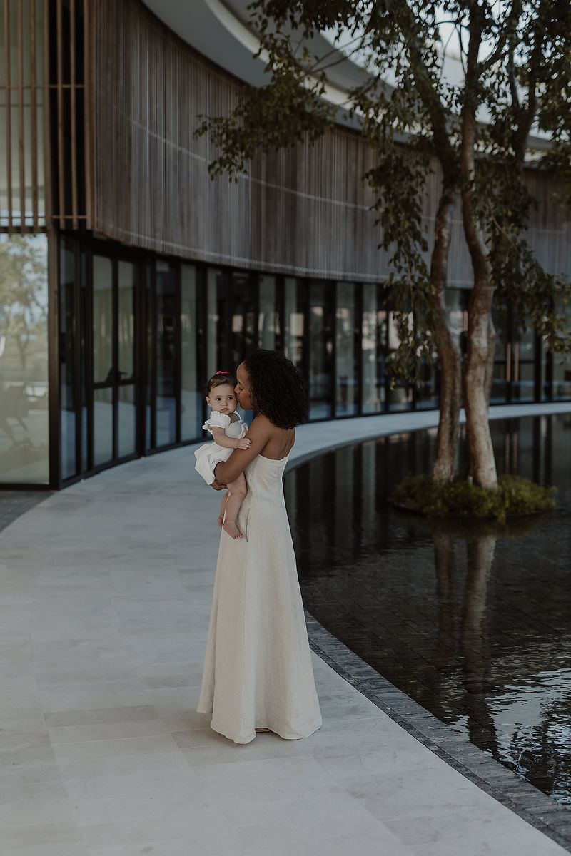 Mother holding daughter by water feature at luxury resort in Riviera Maya family photoshoot.