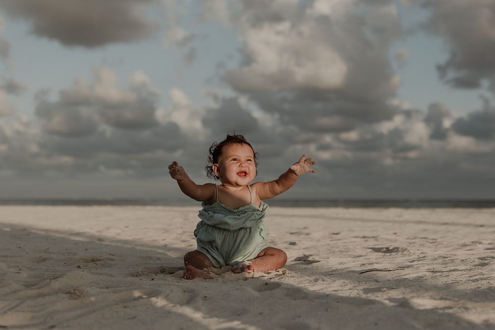 Little girl playing happily on the white sandy beach in Playa del Carmen family vacation photos.