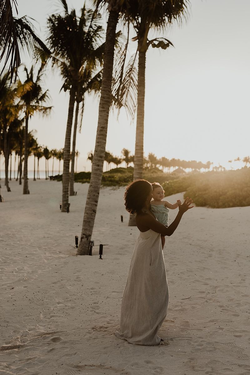 Mother holding daughter during sunset on the beach at The St. Regis Kanai Resort, family photos in Riviera Maya.