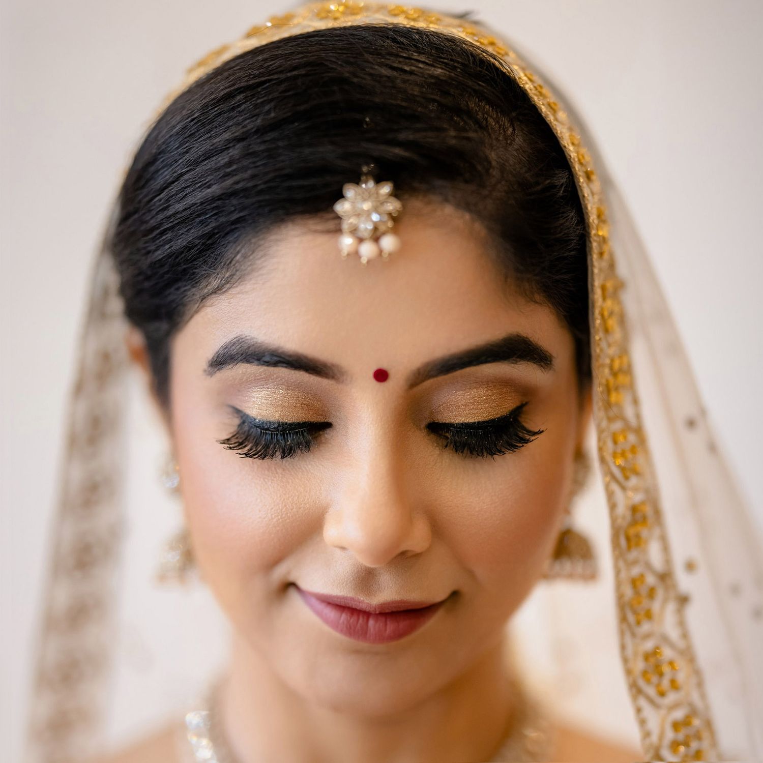 Close-up of traditional Indian bridal makeup and jewelry with golden details.