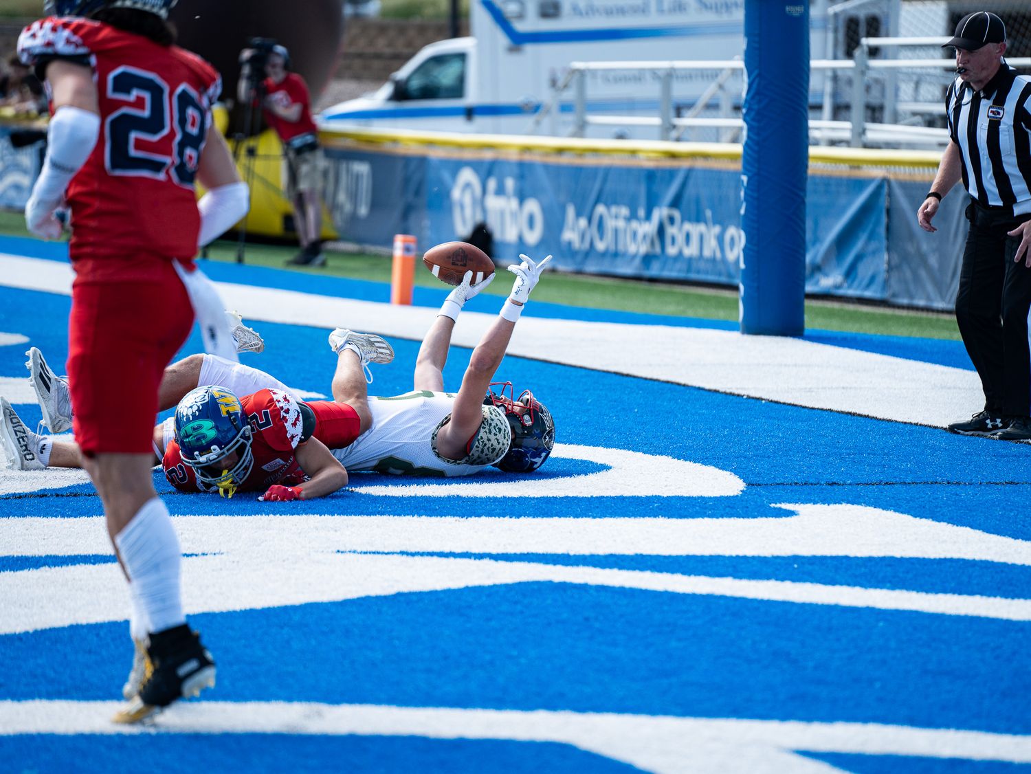 Football player celebrates touchdown by lying in the blue end zone during a game.