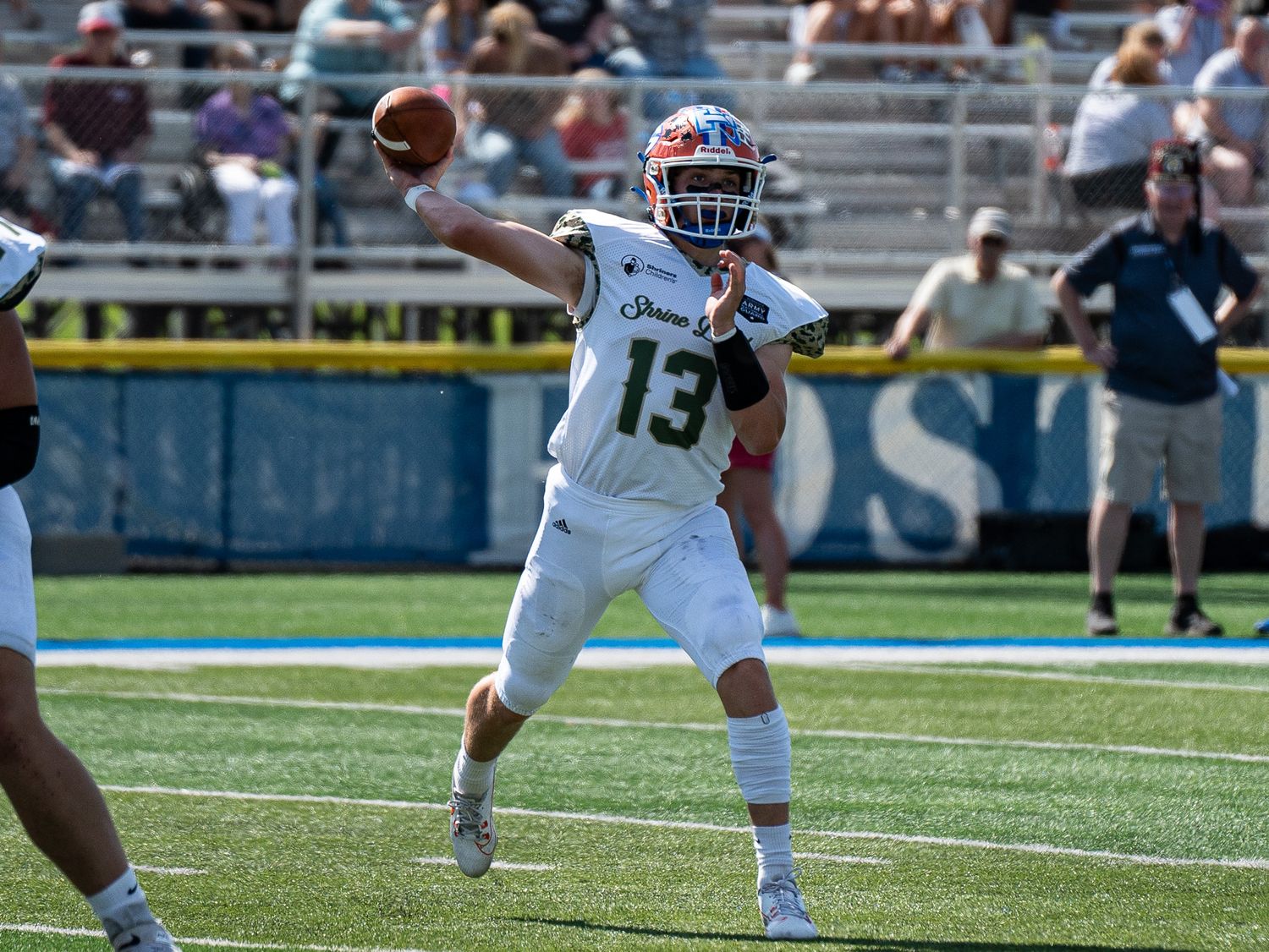 Quarterback in white jersey throws football during outdoor game.