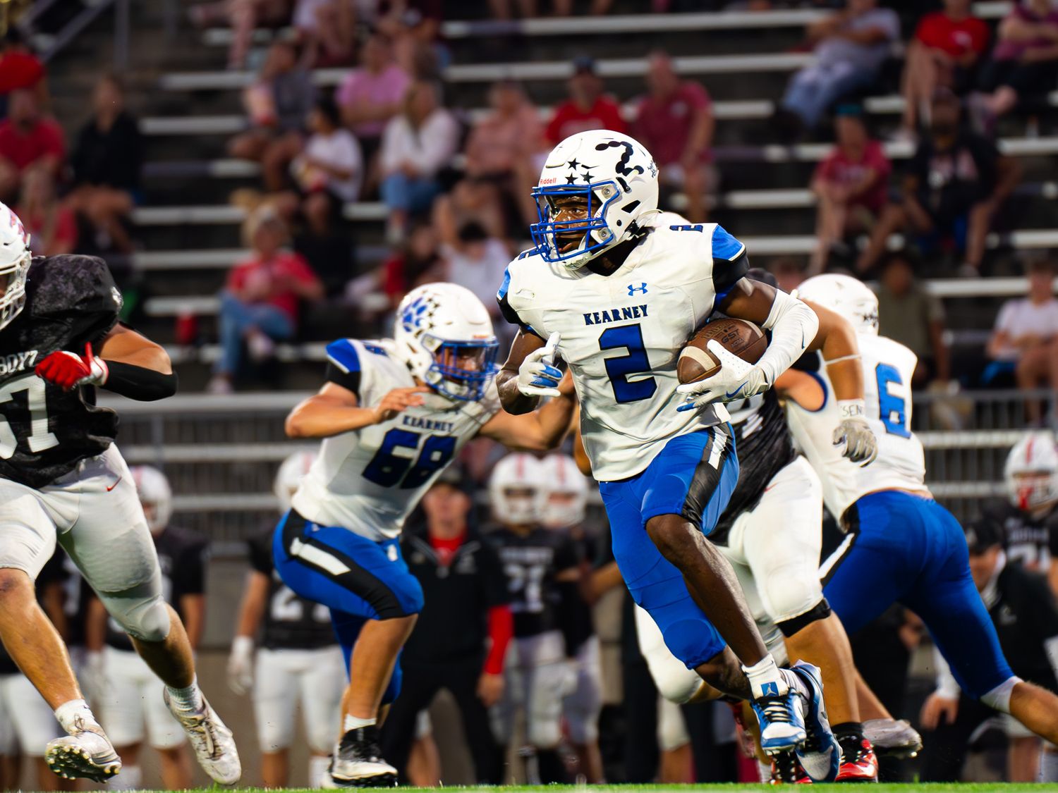 Football player leaps through the air during night game action.
