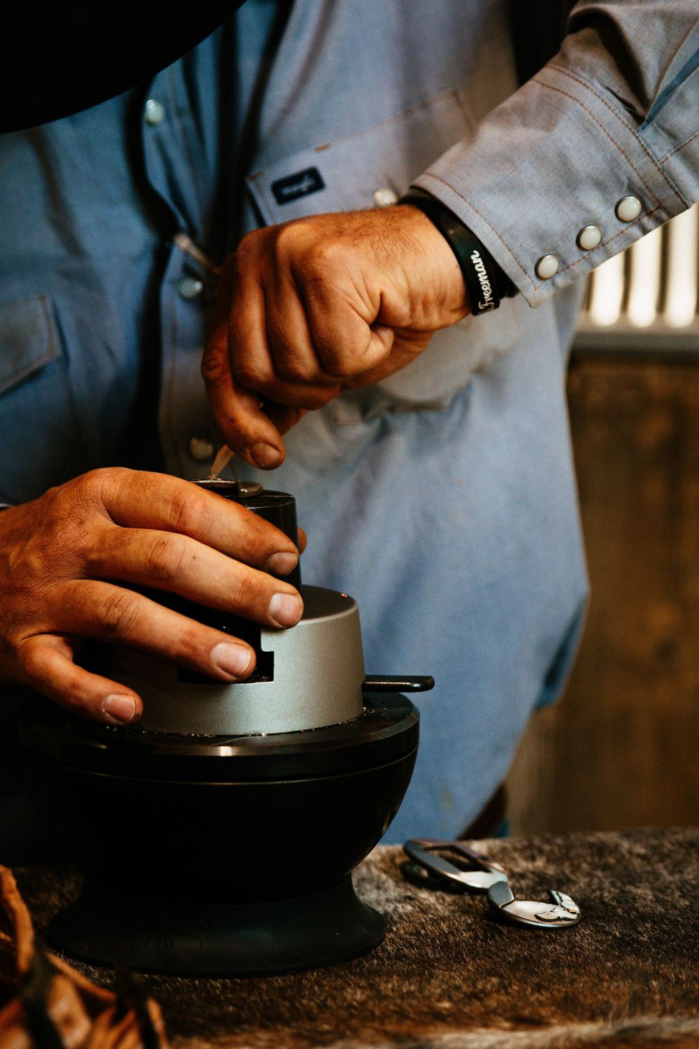 Close-up of hands grinding coffee beans in a modern manual grinder shown in sequential steps.