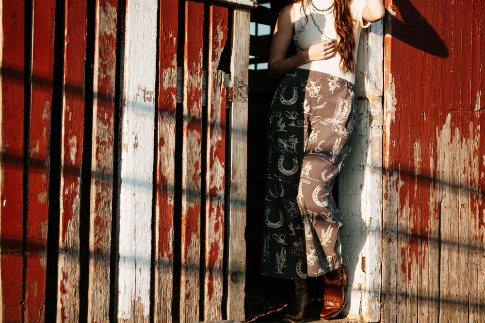 A rustic red barn door with peeling paint and vertical wooden slats creates a weathered, vintage farmhouse aesthetic.