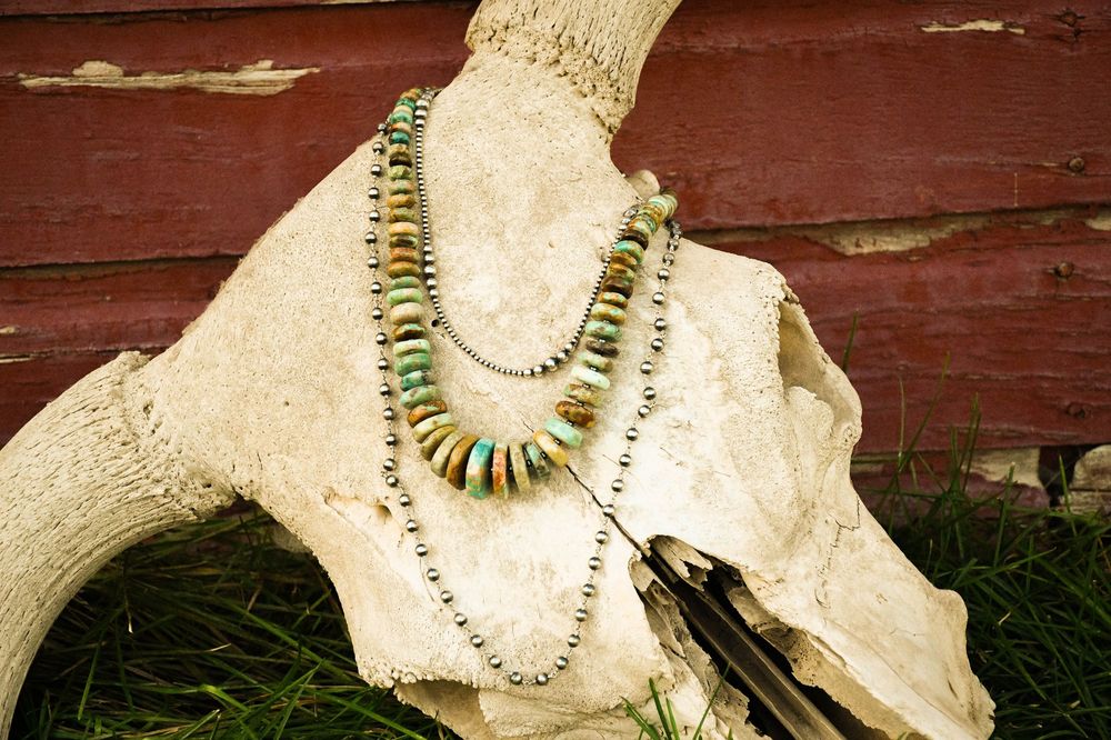 A row of vintage-style turquoise and gold statement necklaces displayed against a rustic wooden background.