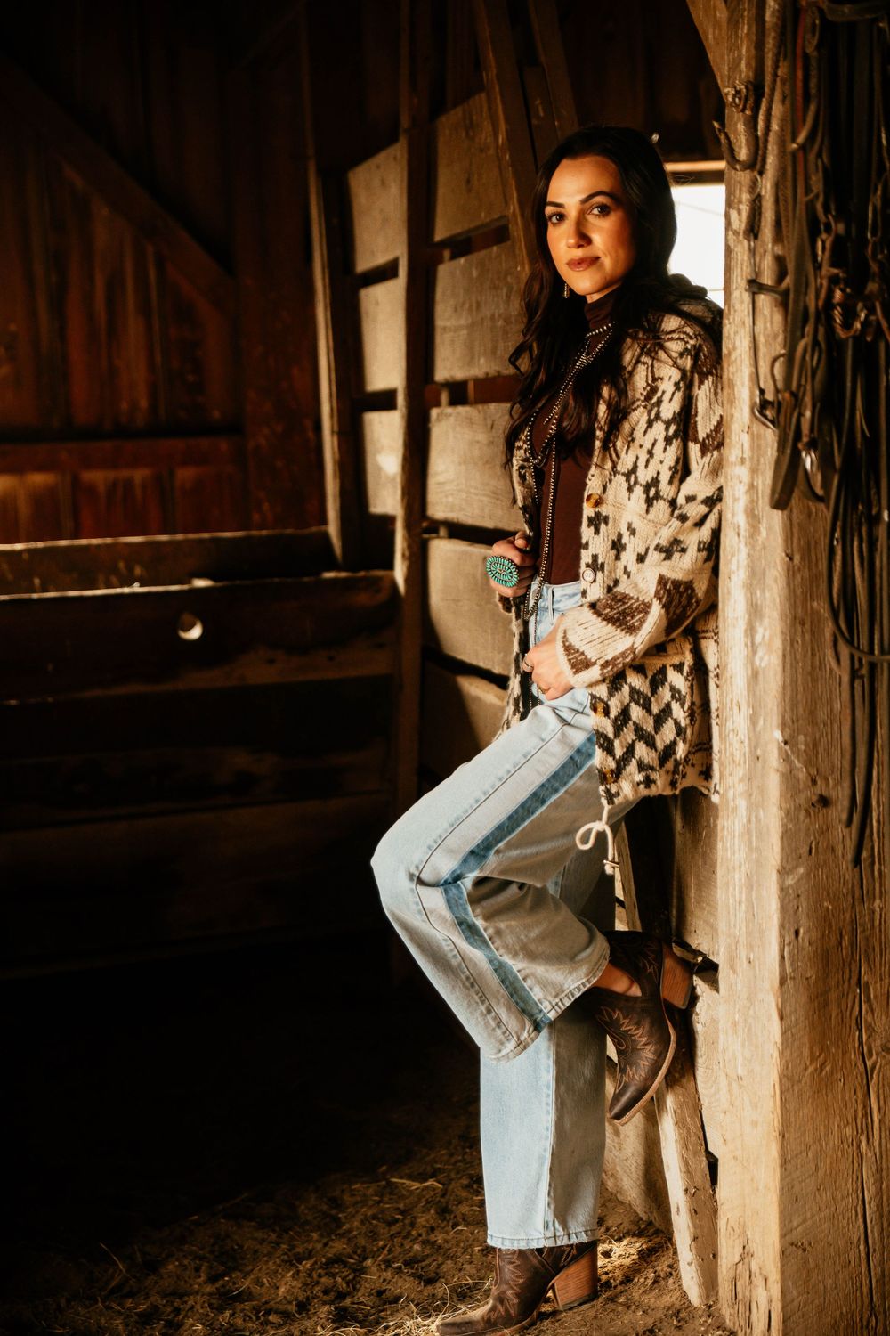 A series of photos showing someone in a patterned top and jeans posing against rustic wooden beams in a barn setting.
